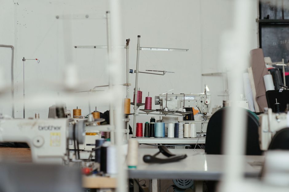 Sarte al lavoro in un atelier artigianale con macchine da cucire e tessuti